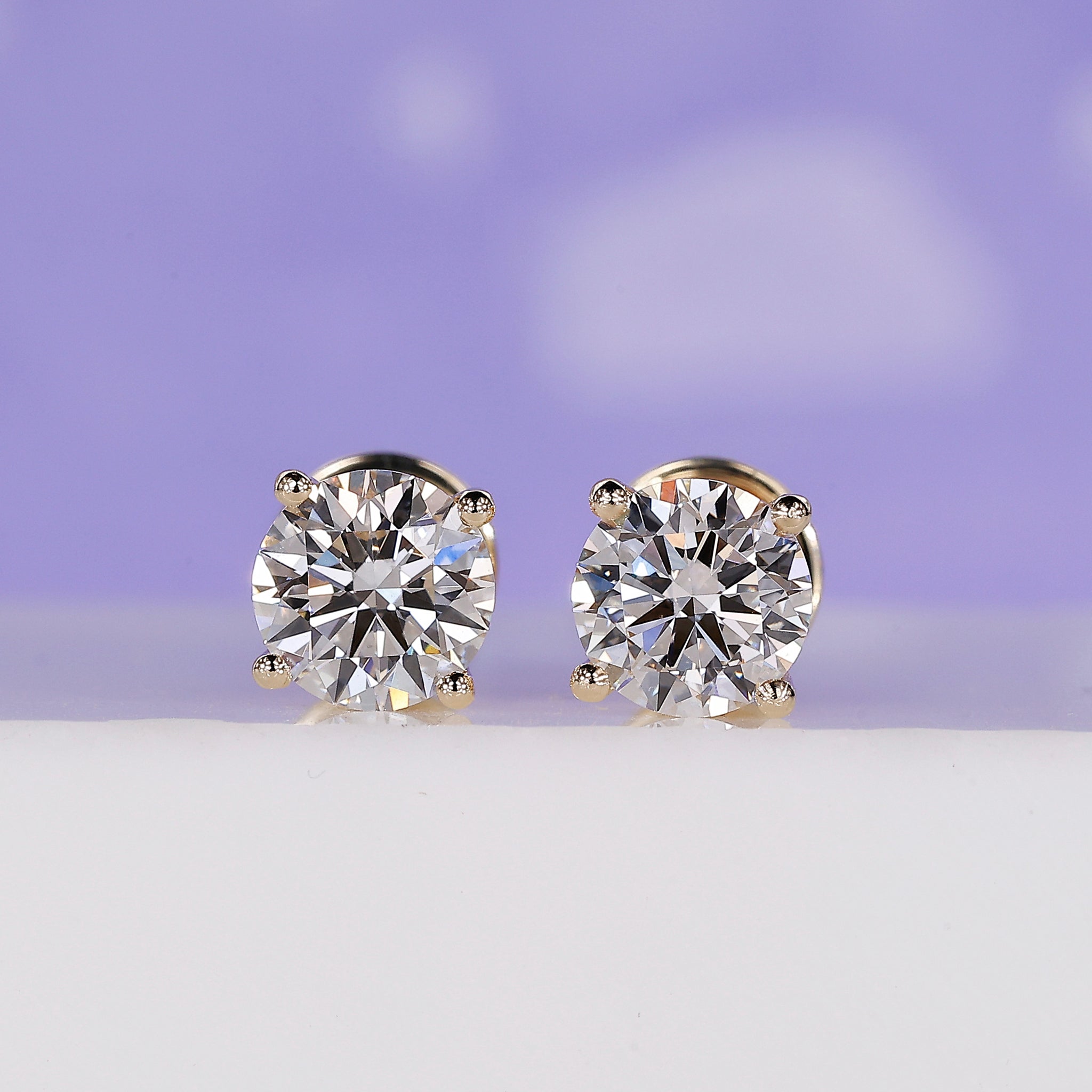 Gold stud earrings with round lab grown diamonds in 4 prong setting.