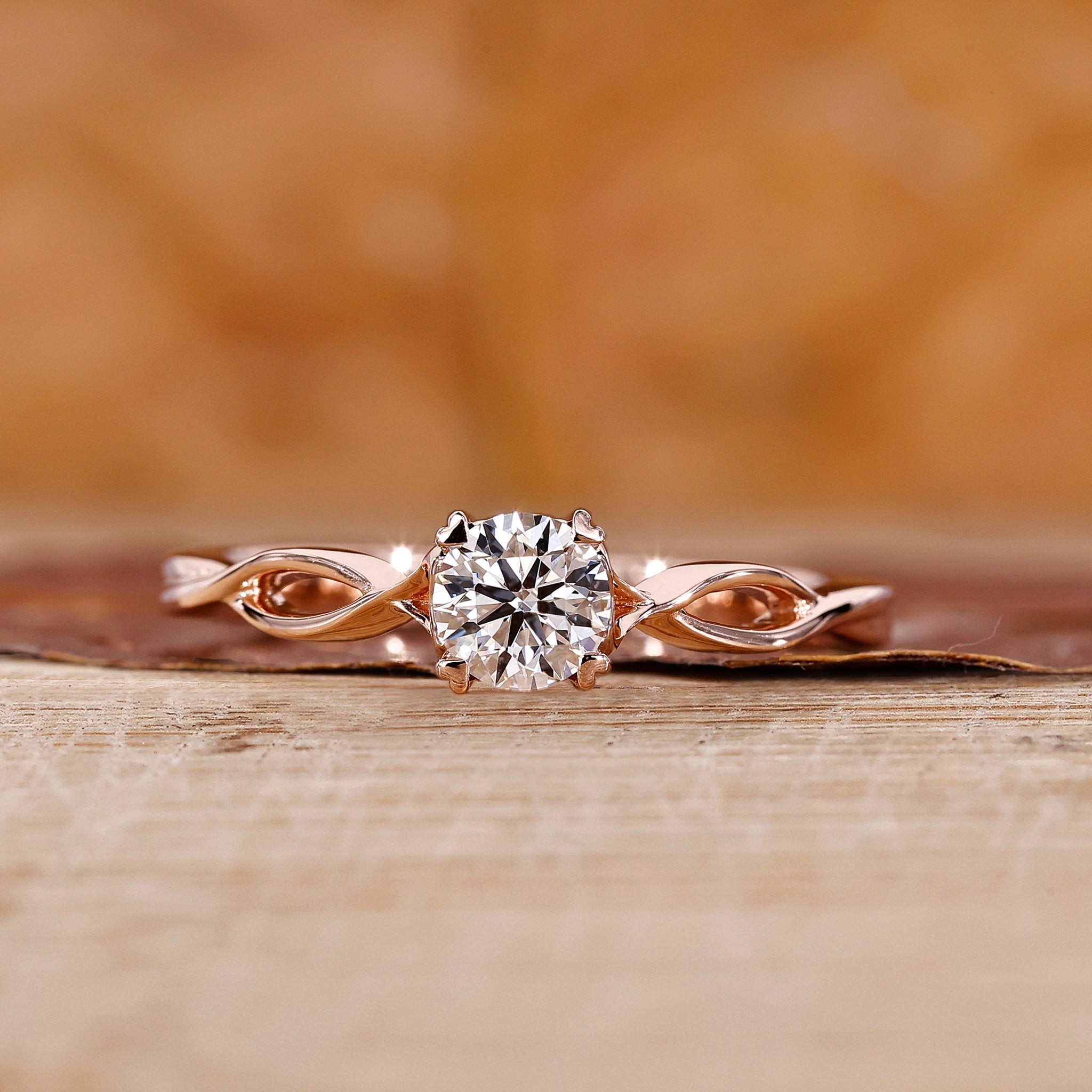 Round diamond ring with twisted shank in rose gold for UK engagement ring.
