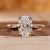 Gold oval diamond engagement ring with hidden halo and round side stones.
