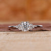 Round diamond engagement ring with round side diamond in muse setting.
