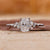 Elongated cushion ring with round side stones in white gold.

