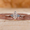 Dutch marquise diamond ring features cyan blue side stones.
