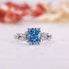 Blue diamond engagement ring with cushion cut centre in white gold.

