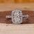 Oval diamond engagement ring with round diamond halo in white gold.
