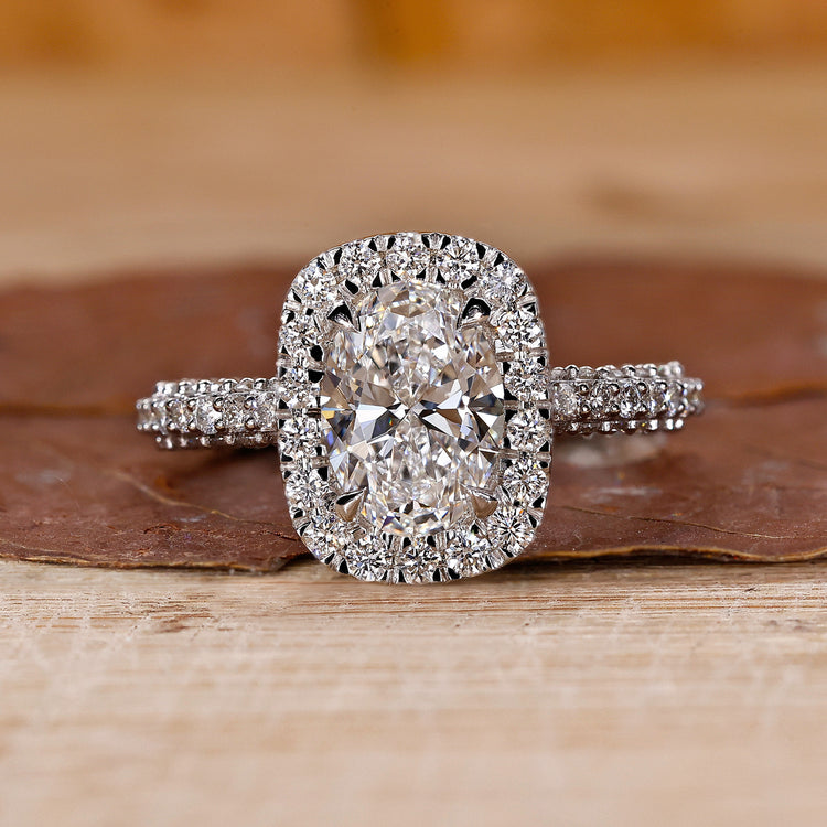 Oval diamond engagement ring with round diamond halo in white gold.
