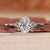 Oval cut engagement ring with round side stones in white gold.
