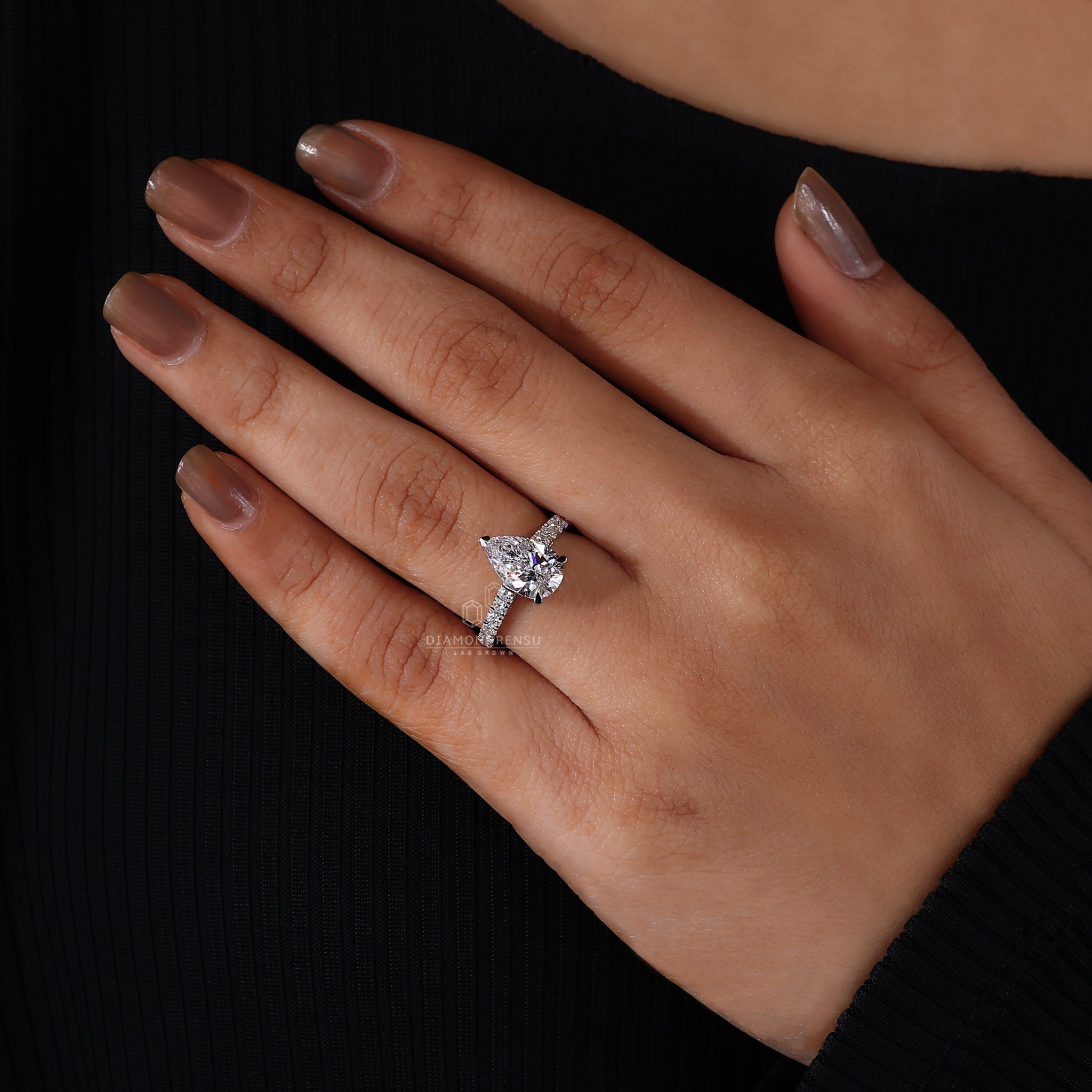 Model wearing a pear cut engagement ring with a sparkling diamond