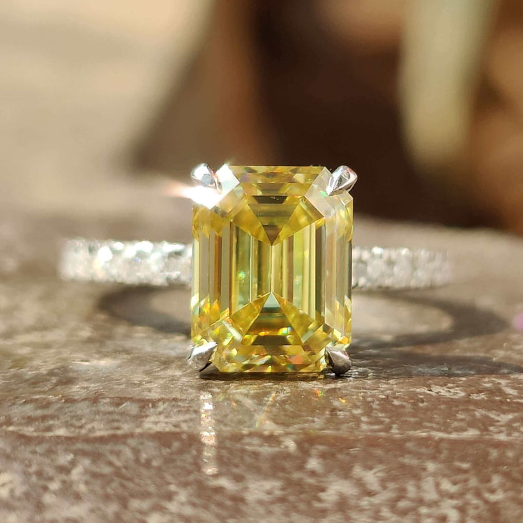 Emerald cut bright yellow moissanite ring with hidden halo design.
