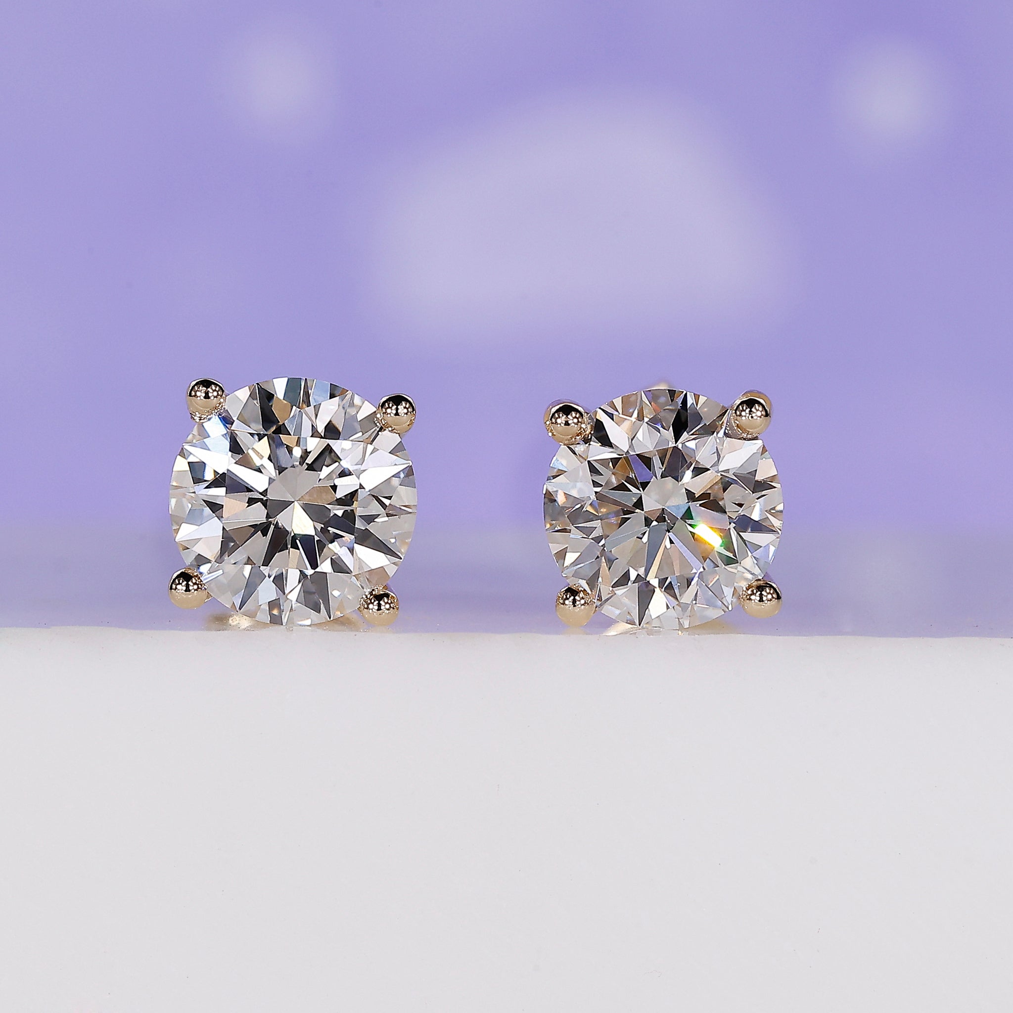 Round diamond stud earrings in yellow gold.