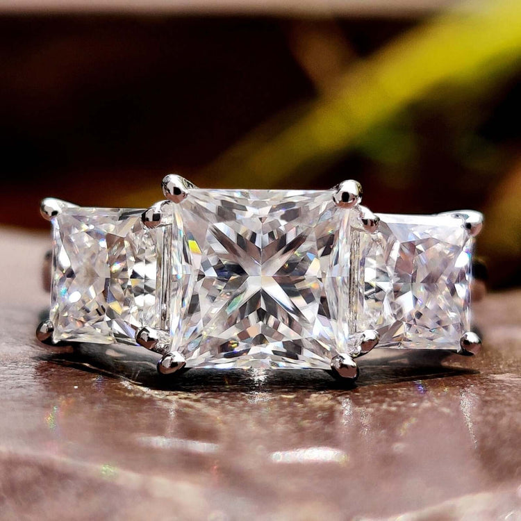 Three stone moissanite ring with princess cut center.

