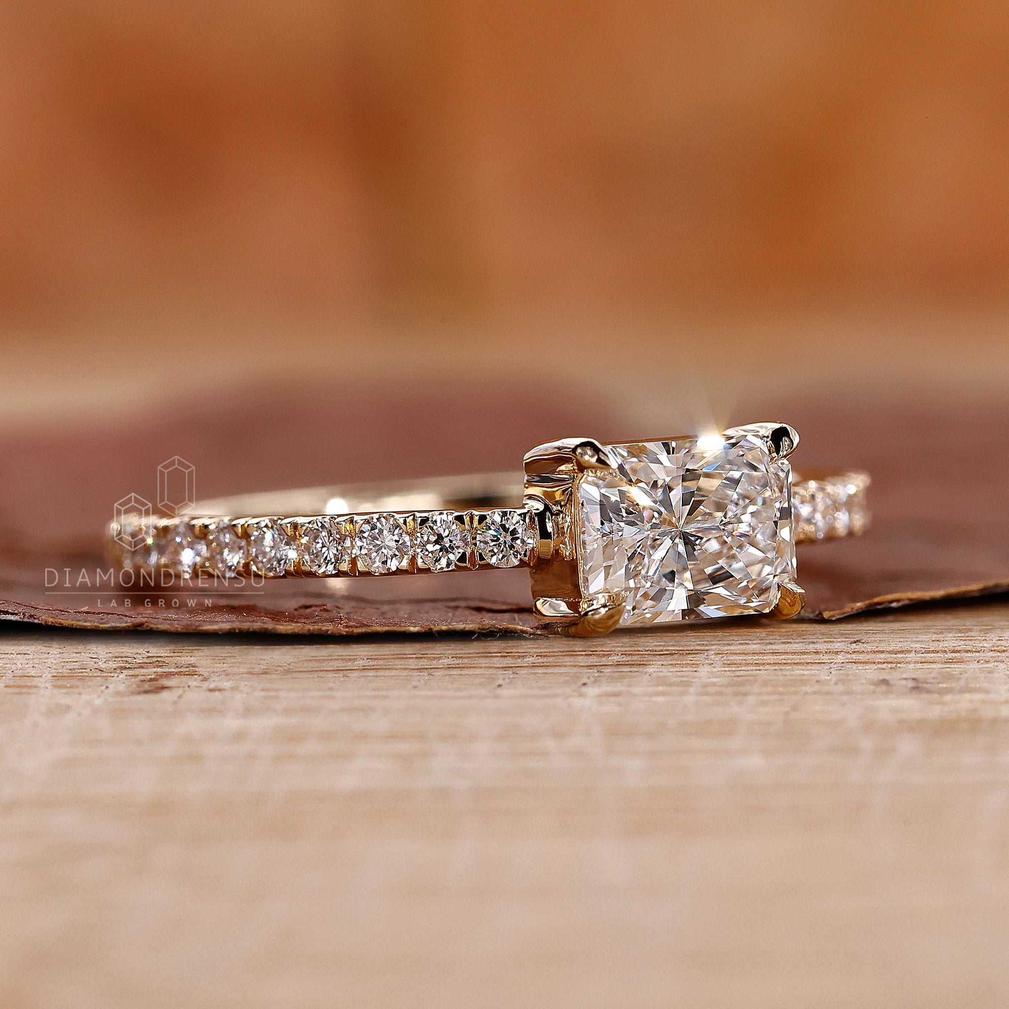 Proposal engagement ring with radiant diamond and yellow gold band.
