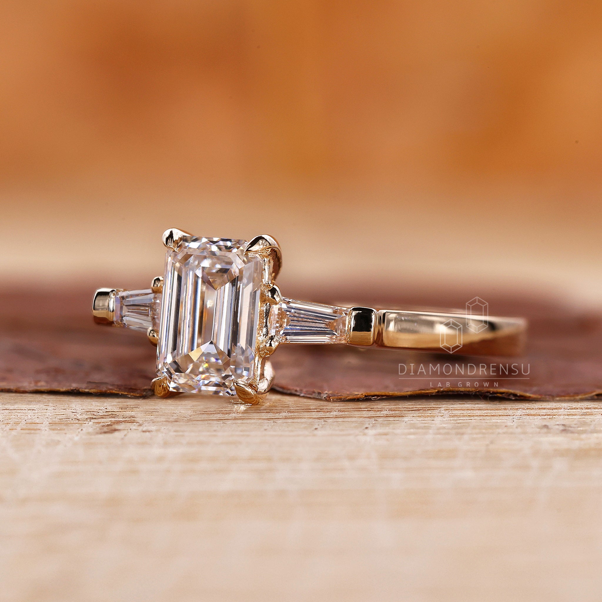 UK engagement ring with 2 side tapered baguette diamond set in yellow gold.
