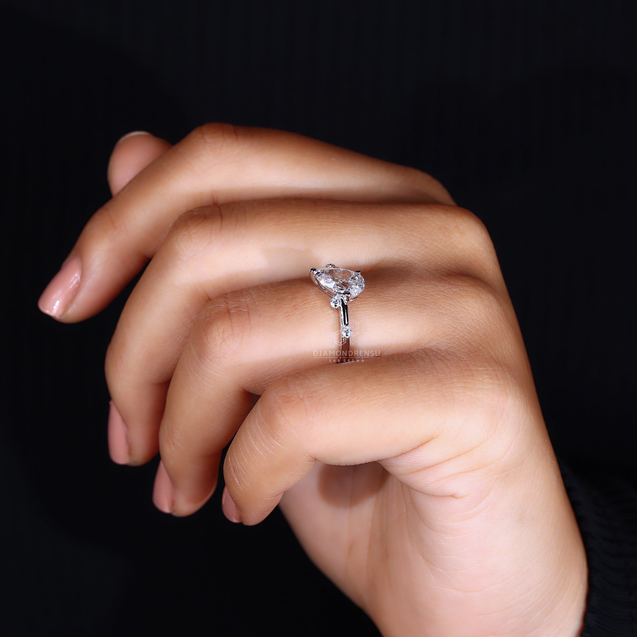 Close-up of a model wearing a diamondrensu ring with a pear-shaped diamond and IGI certified lab-grown diamond.