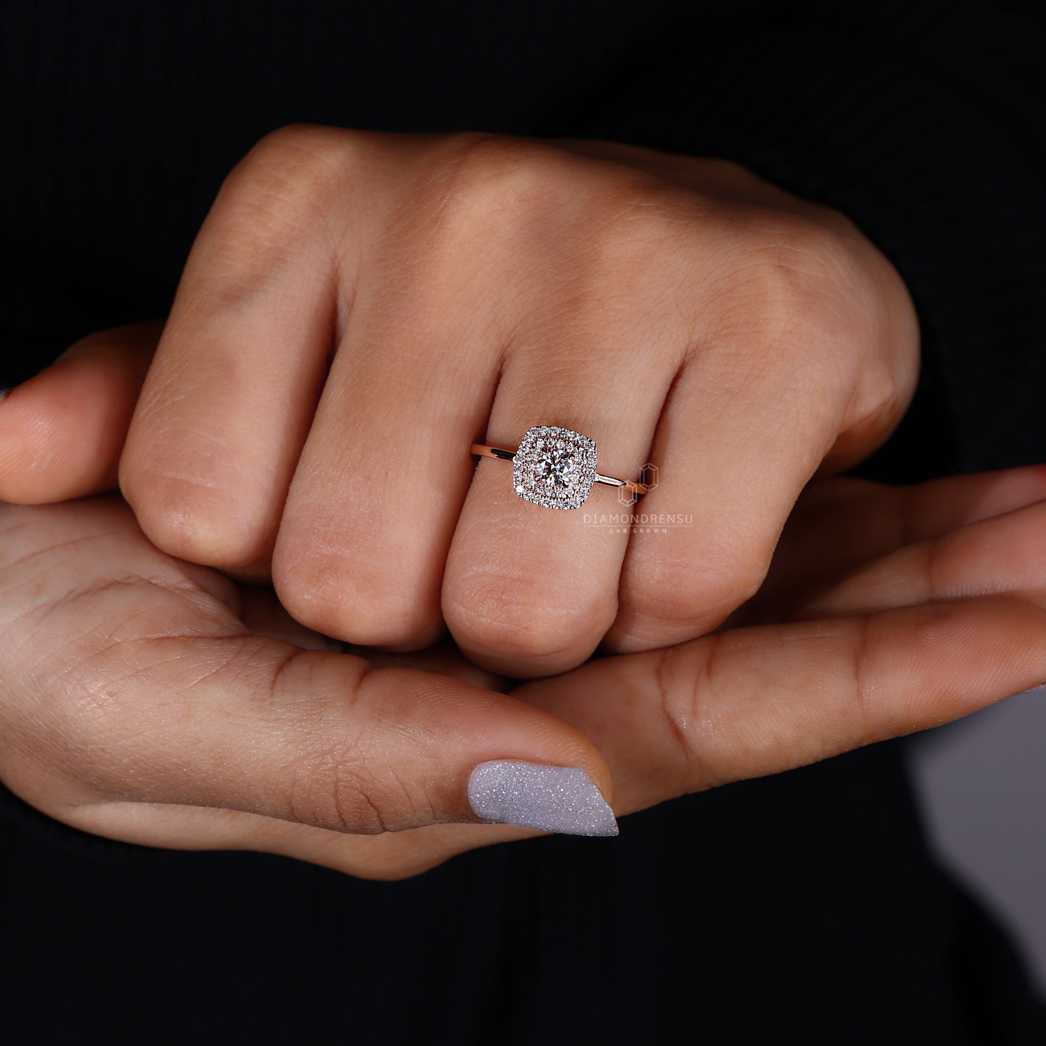 Close-up of a female hand wearing a stunning double halo round engagement ring, the central diamond brilliantly highlighted by the surrounding halos, set against a soft, neutral background.