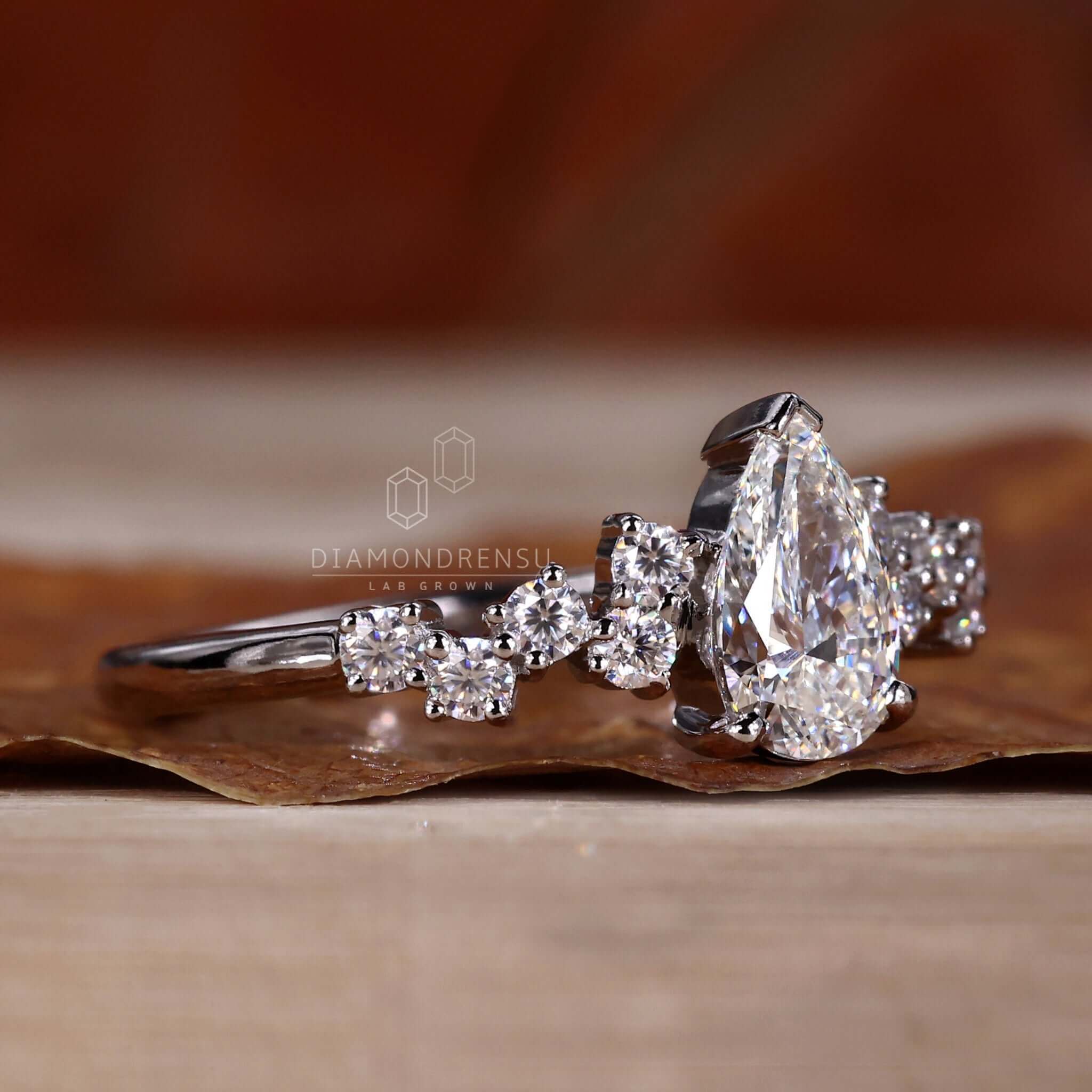 Pear diamond ring with round side stones in a classic 4 prong diamond ring style for women.
