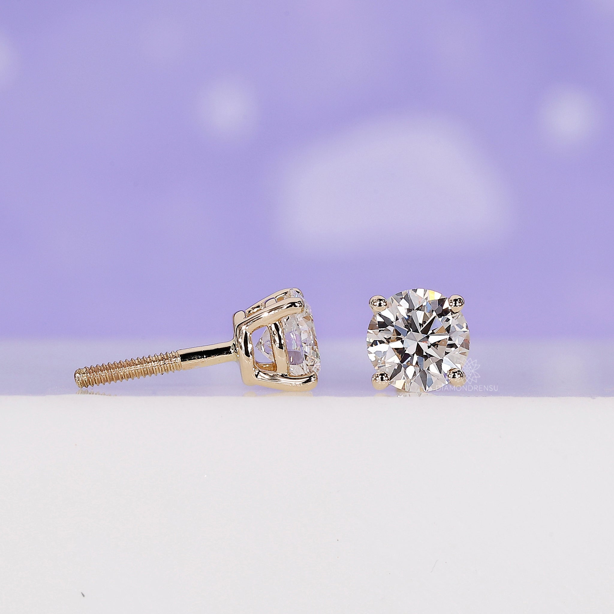 Prong setting earrings designed as classic yellow gold diamond studs.