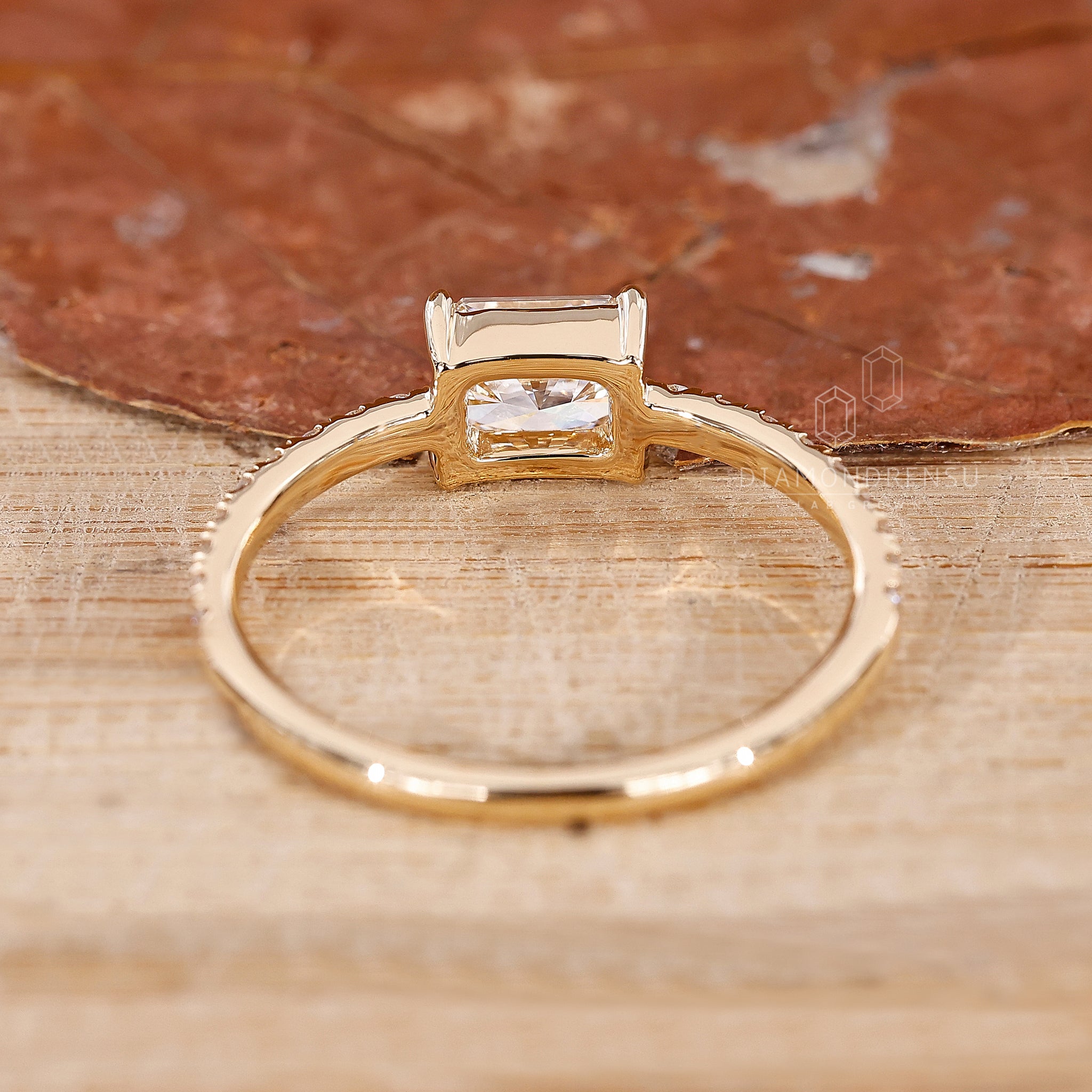 Yellow gold ring with east to west radiant diamond and pave set band.
