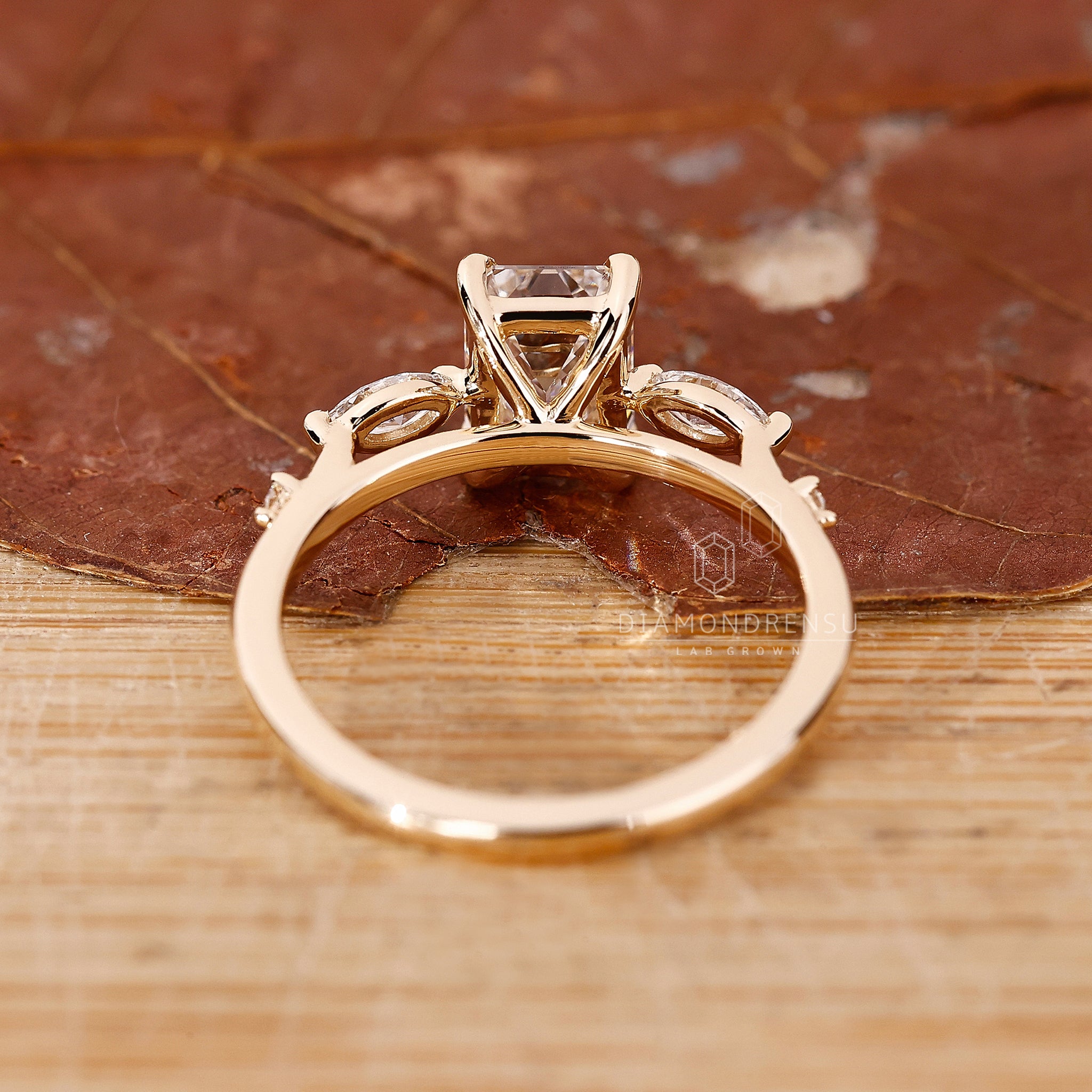 Lab diamond ring featuring emerald center and 2 marquise, 2 round side stones.
