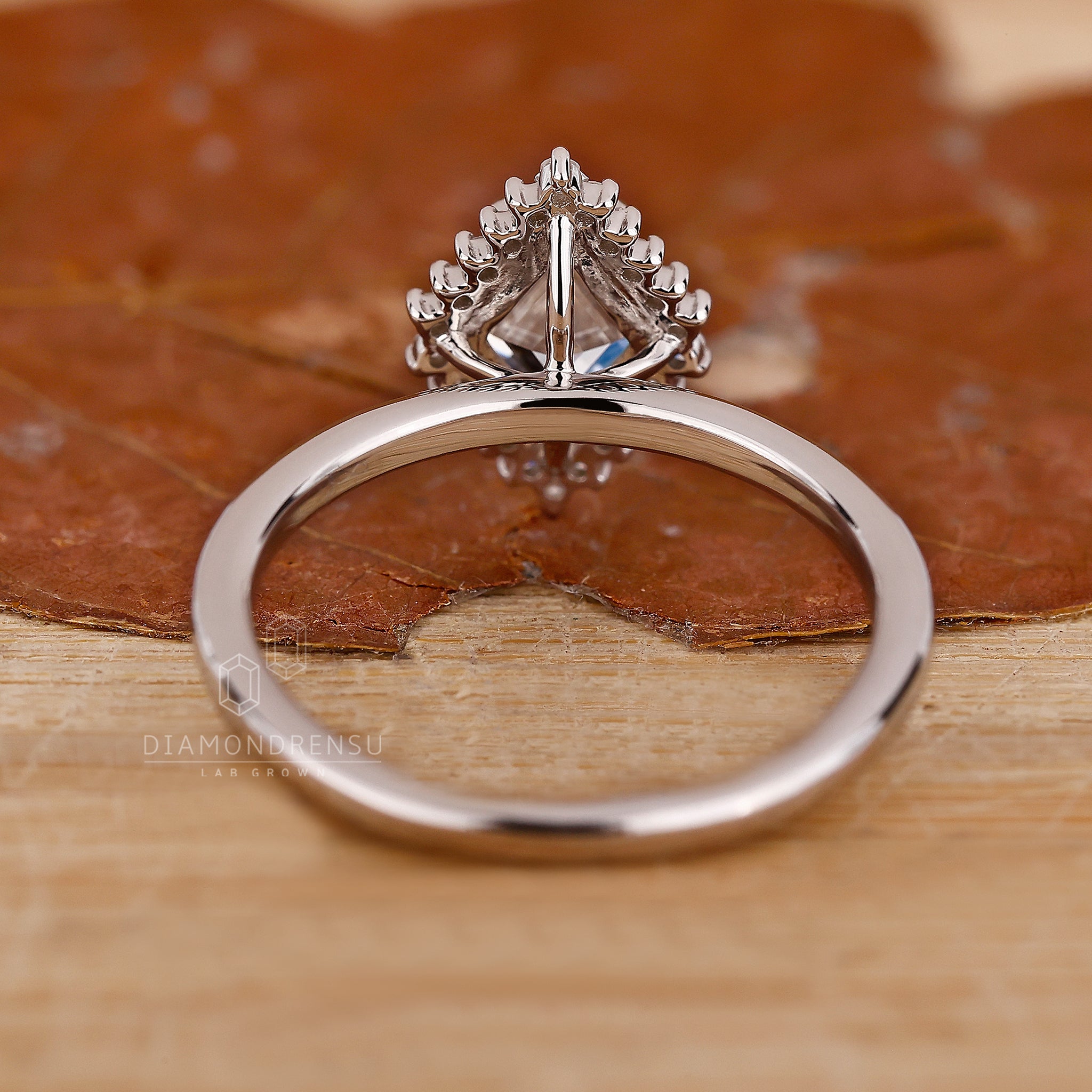 White gold ring with prong set lozenge cut diamond and halo design.
