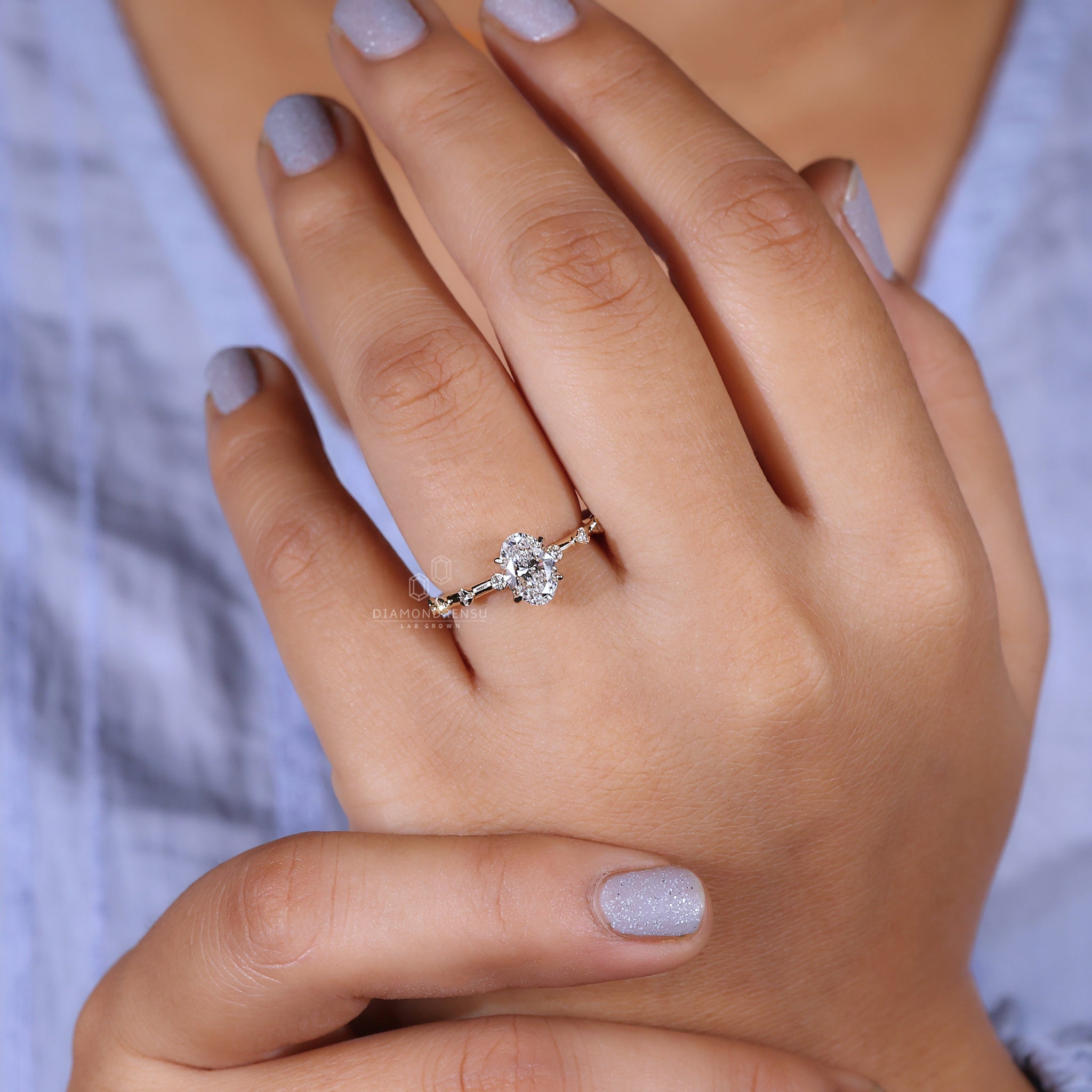 Hand showing a hidden halo engagement ring with a stunning oval cut diamond and yellow gold band.