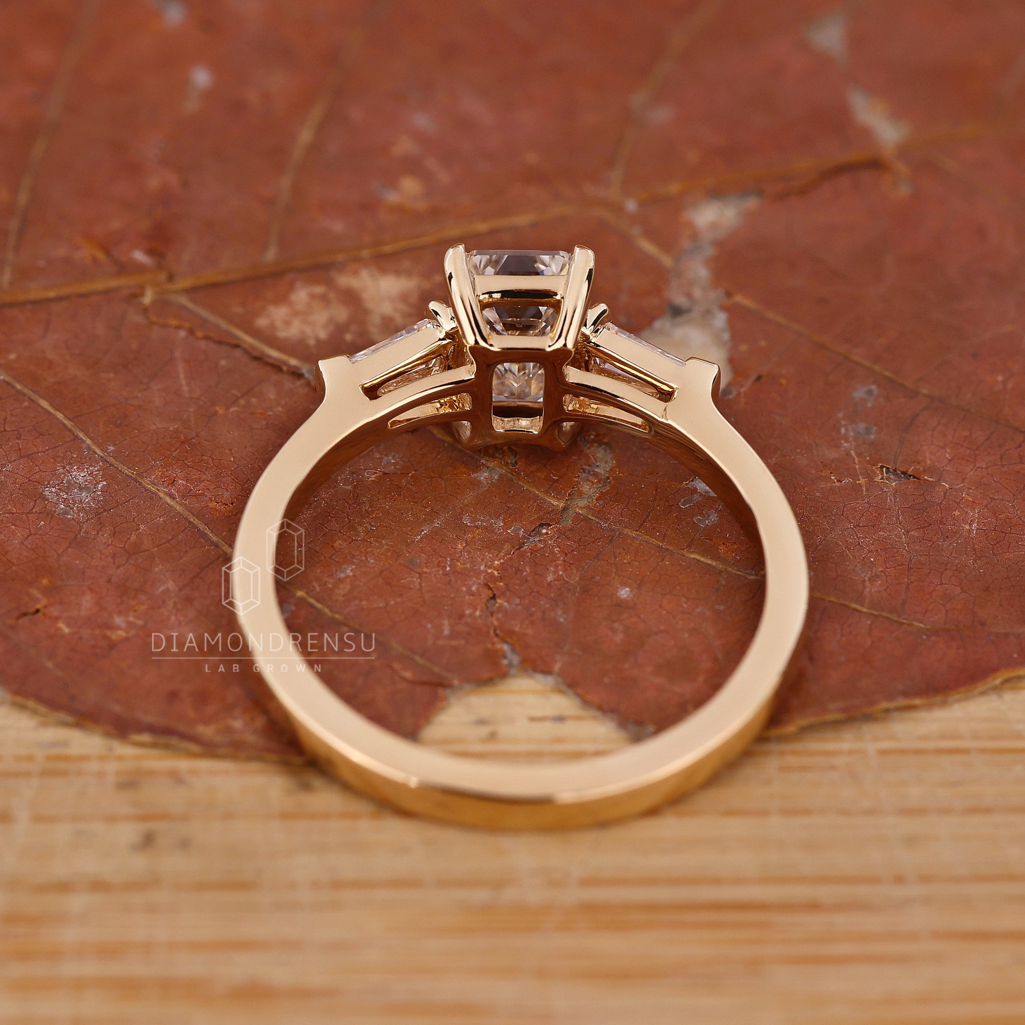 Emerald diamond engagement ring featuring tapered baguette side diamond ring design.
