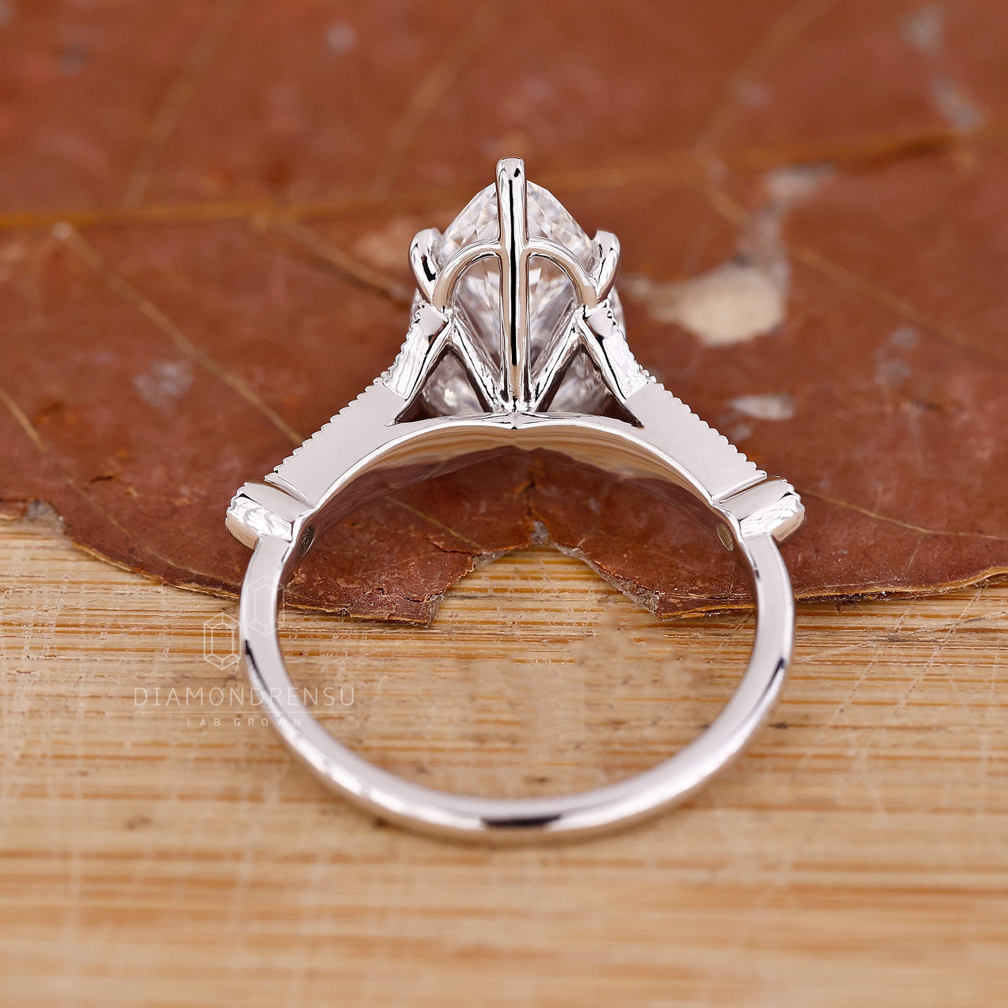 White gold ring with pear diamond center and round side diamonds.
