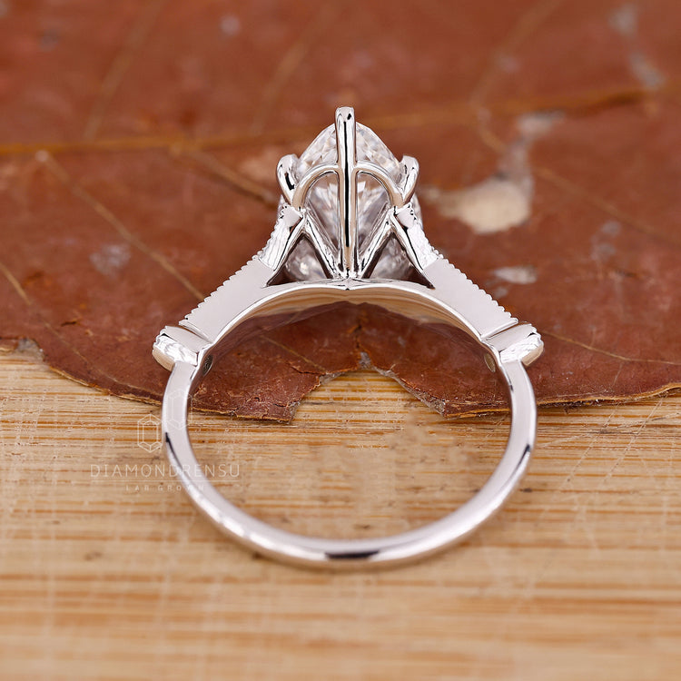 White gold ring with pear diamond center and round side diamonds.
