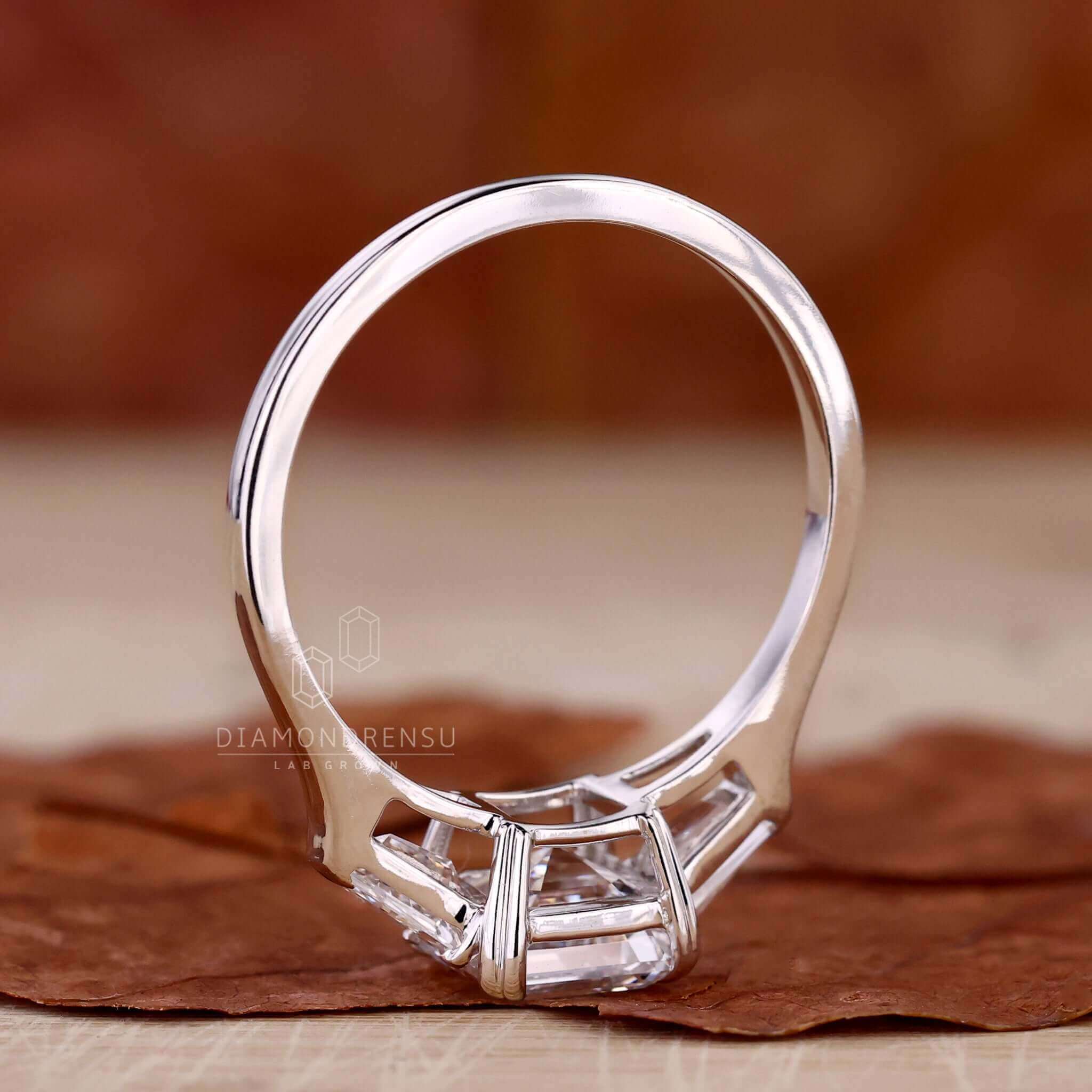 Three stone diamond ring with a stunning asscher cut centre stone and claw prong engagement ring style.
