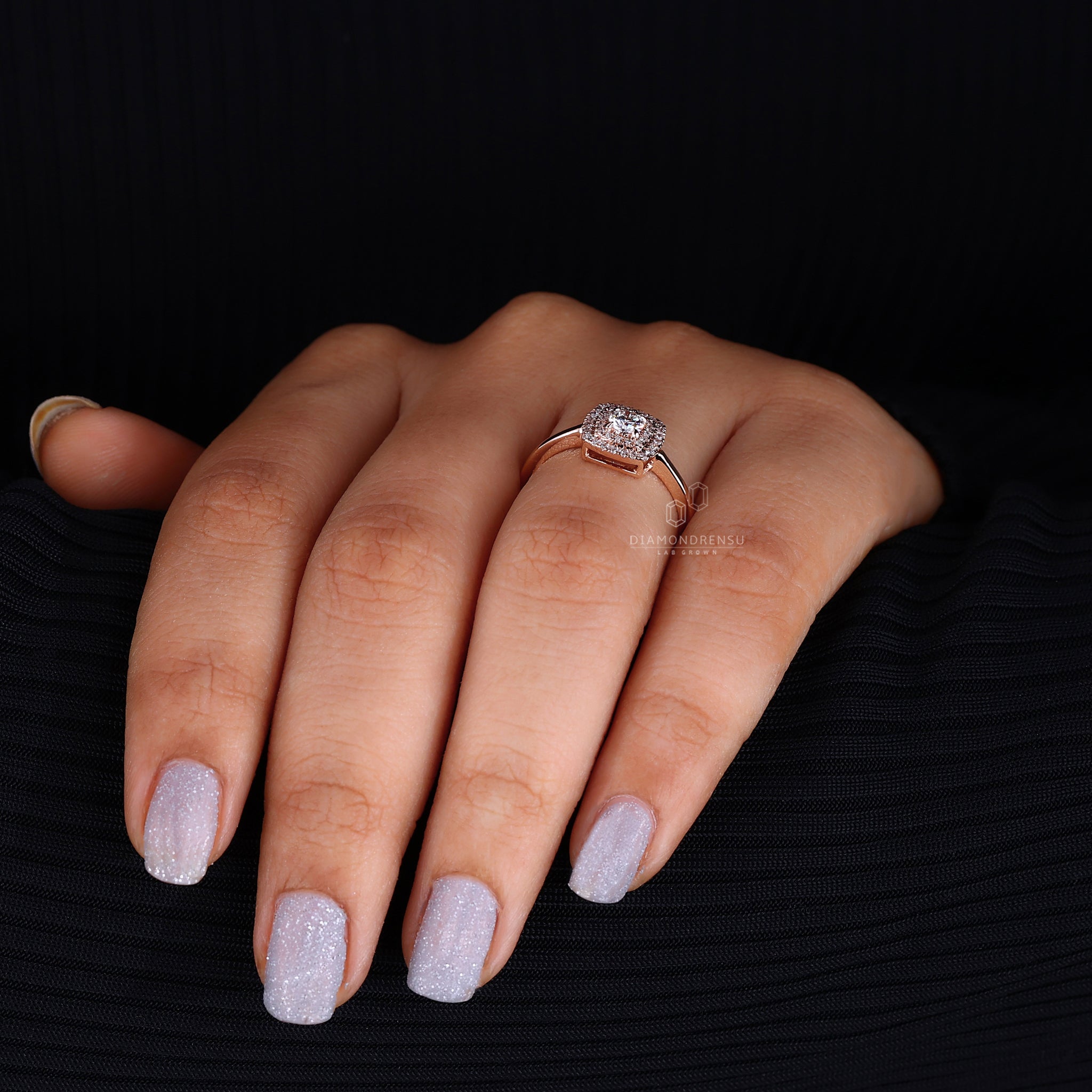 A close-up on-model shot of a round brilliant cut diamond ring on a woman’s hand, the diamond's cut perfectly showcased by the light, set in an elegant double halo design on a silver band.