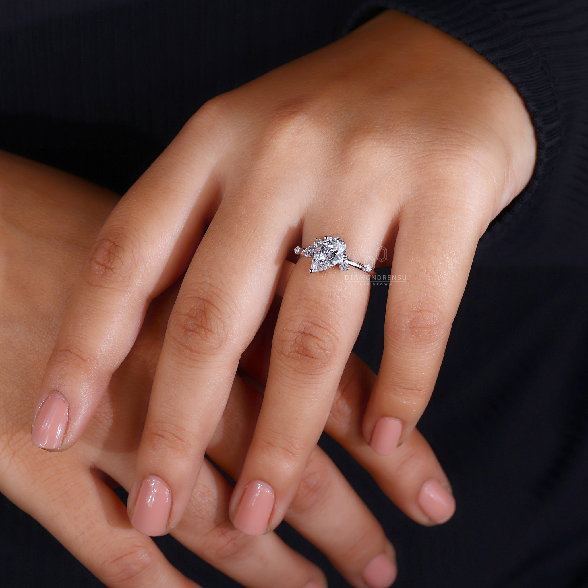 White gold ring showcasing a pear shaped diamond and side stones.