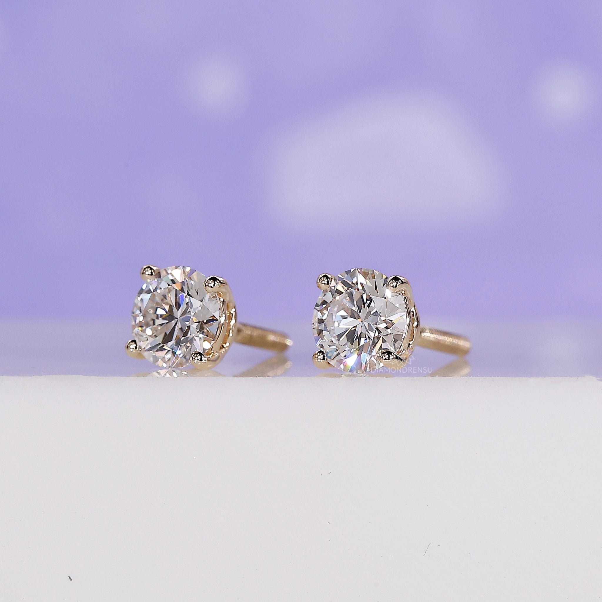 Custom diamond earrings featuring round cut studs in yellow gold.