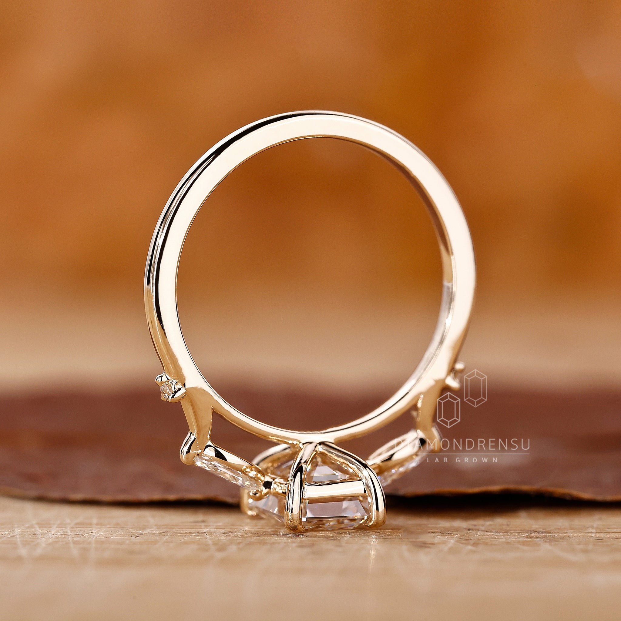 Proposal ring with emerald center diamond and prong set side stones.

