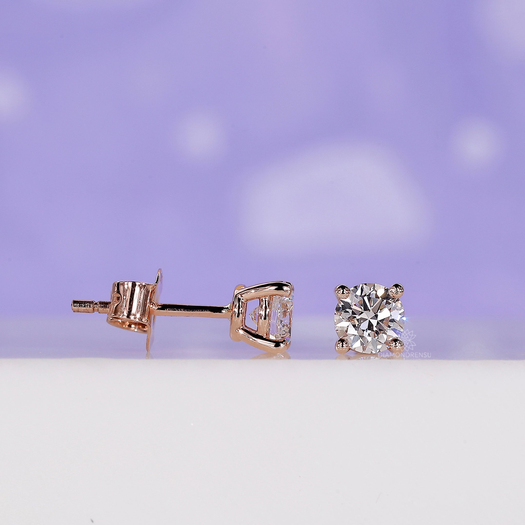 Custom diamond earrings featuring round studs in a rose gold finish.