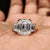 Three stone engagement ring with emerald cut moissanite and trapezoid sides.
