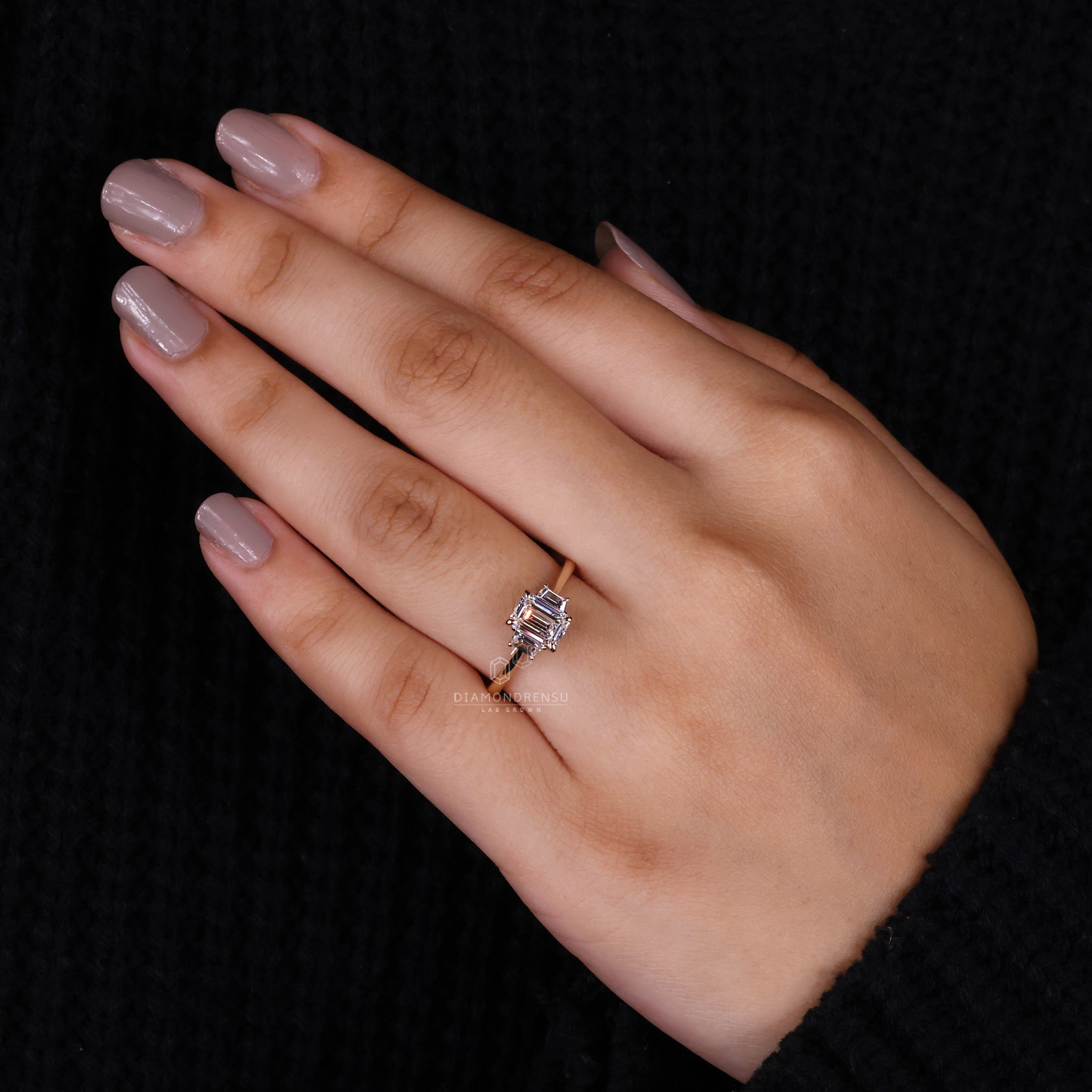 Model wearing a lab grown diamond engagement ring, showcasing the brilliance of the emerald cut and trapezoid diamonds