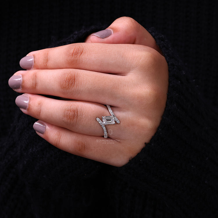 Custom diamond ring with emerald cut centre stone and bypass band.
