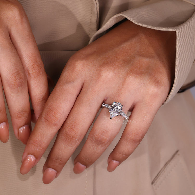 UK engagement ring with pear center diamond and cathedral setting.
