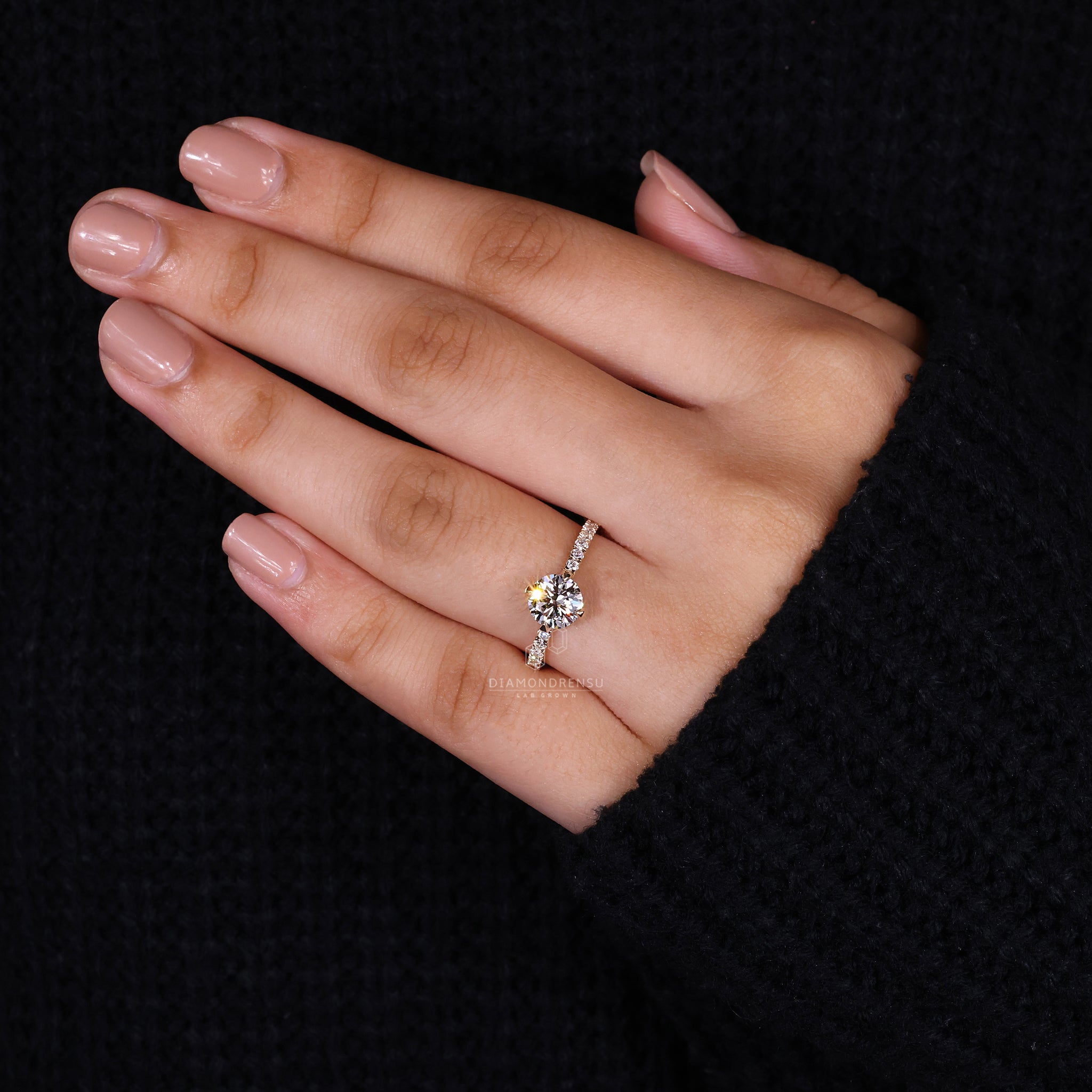 UK engagement ring featuring round diamond and compass prong setting.
