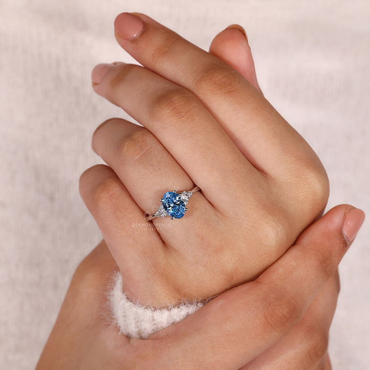 Proposal engagement ring featuring blue oval diamond and side stones.
