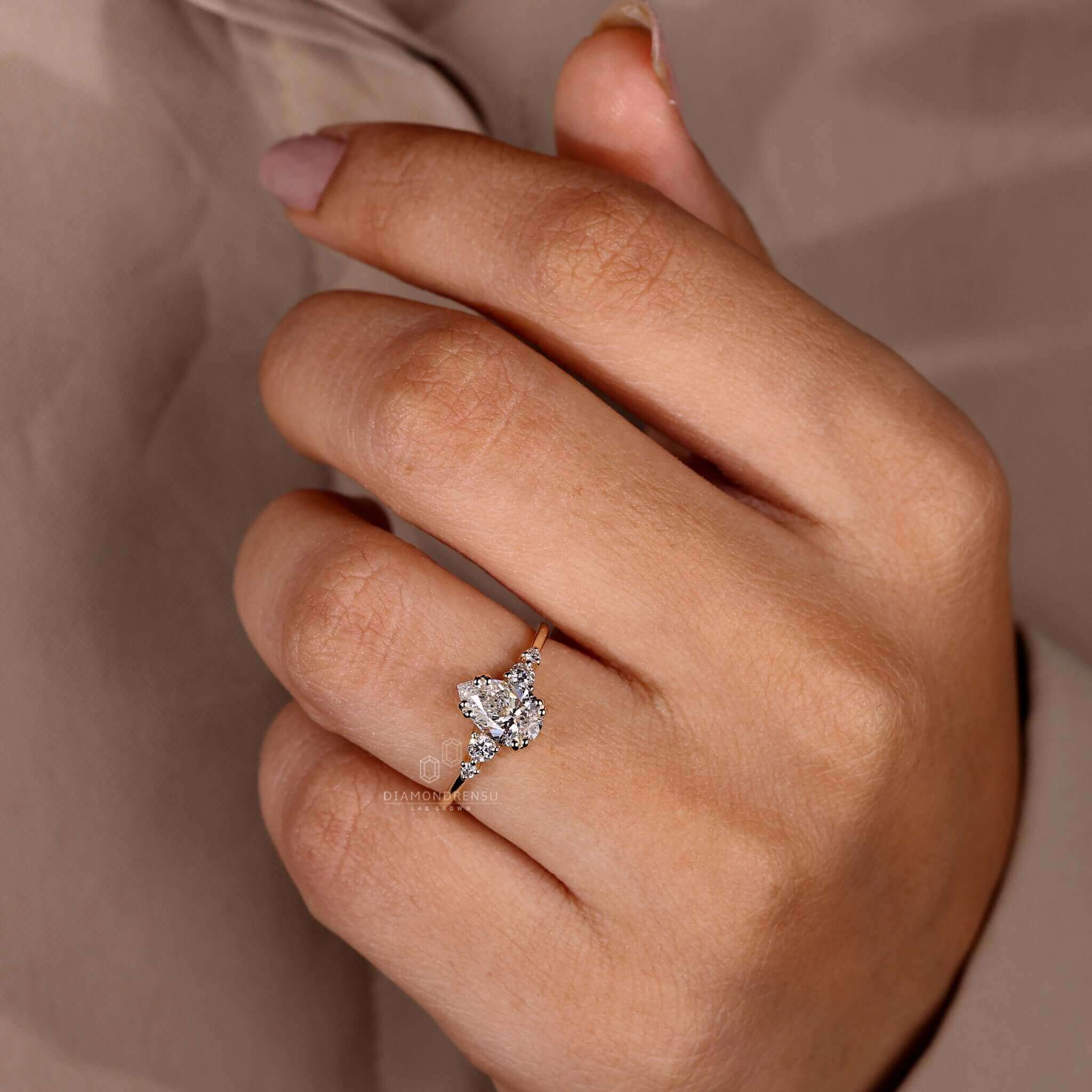 Round cut diamond ring with a pear shaped diamond and 4 prong setting for modern elegance.