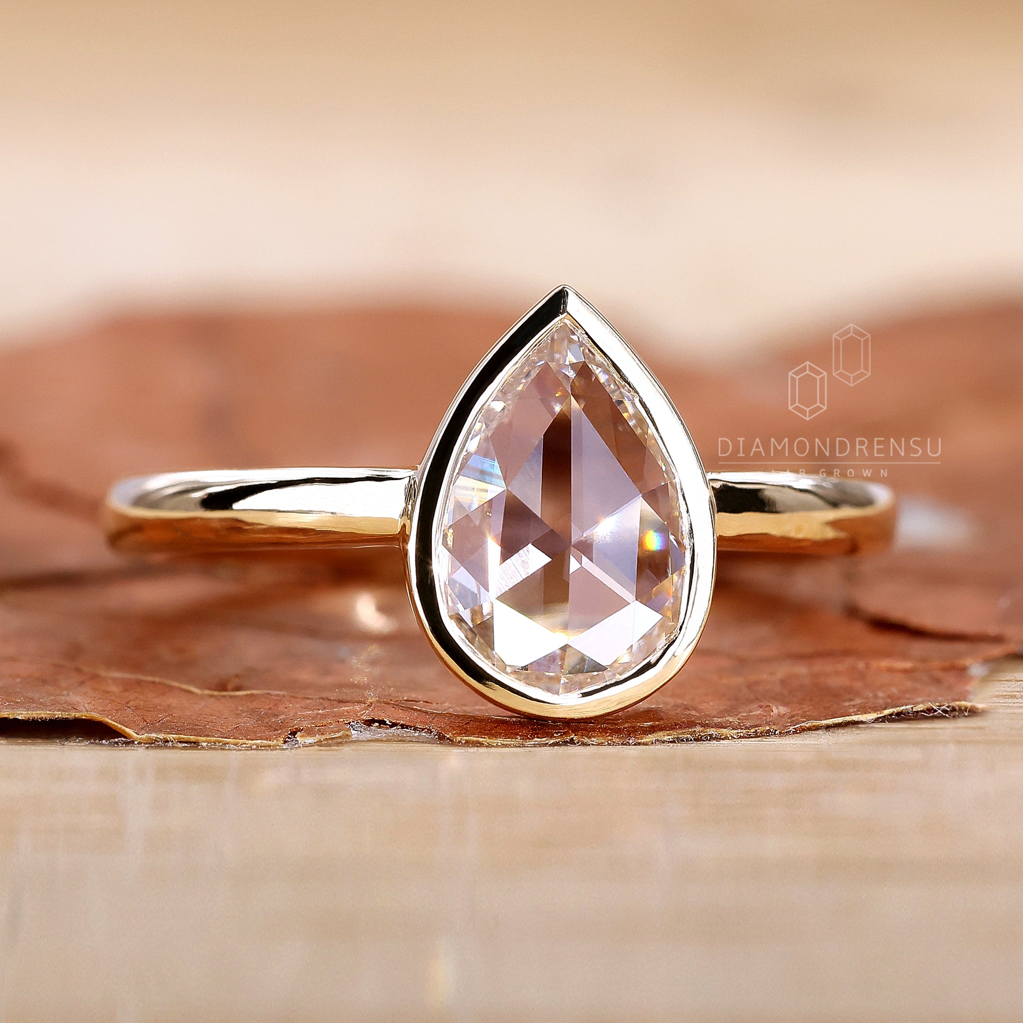 Pear diamond ring in yellow gold bezel setting
