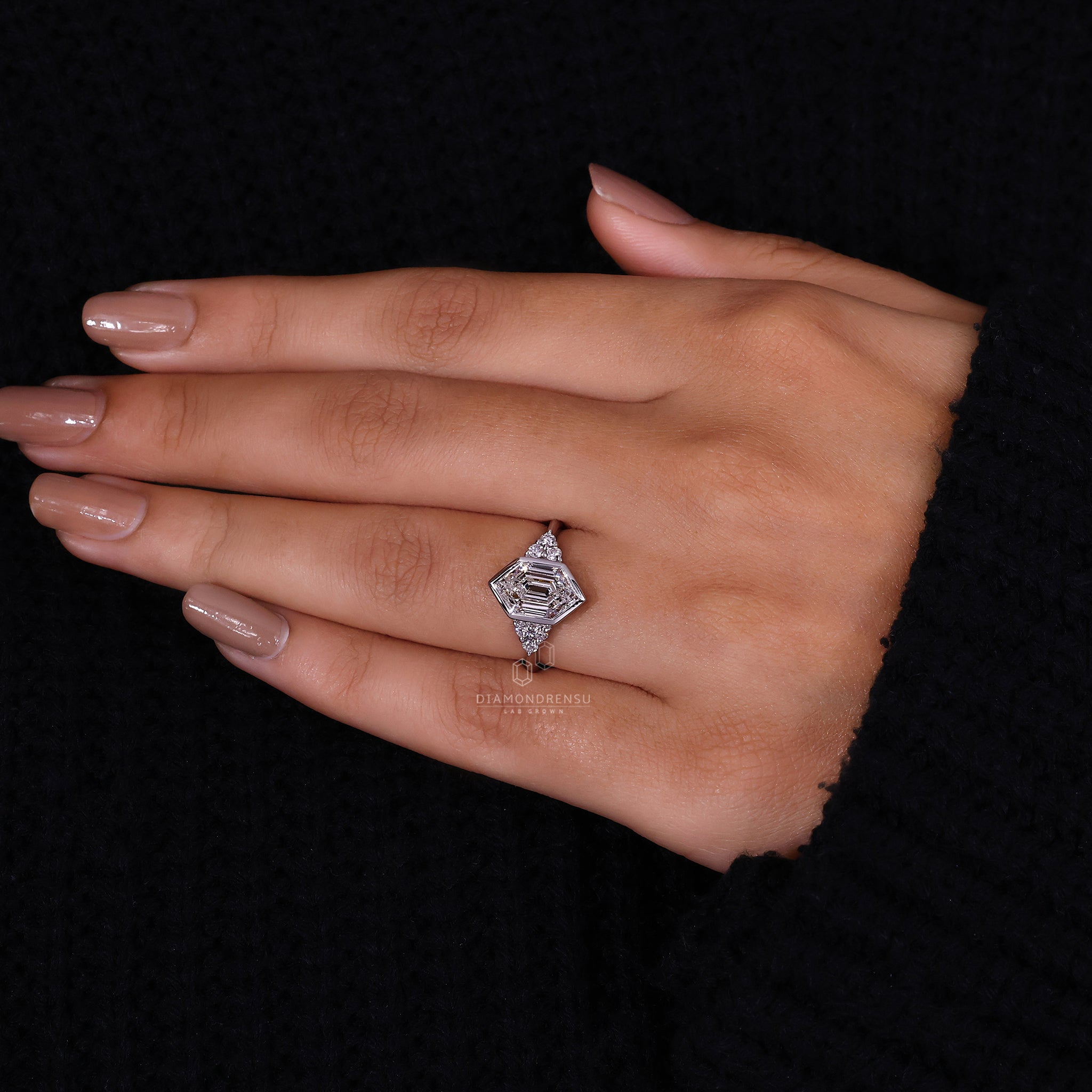 Engagement ring featuring round side stones and a knife edge shank.
