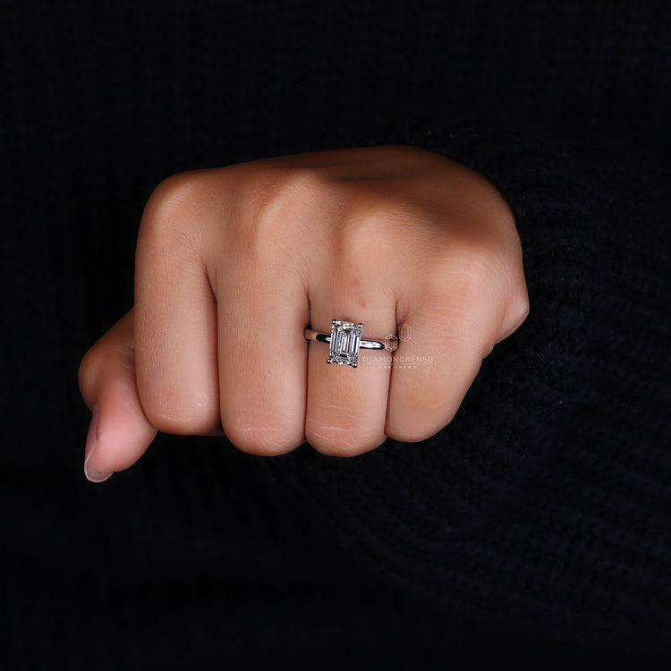 Hidden halo engagement ring featuring an emerald cut stone.
