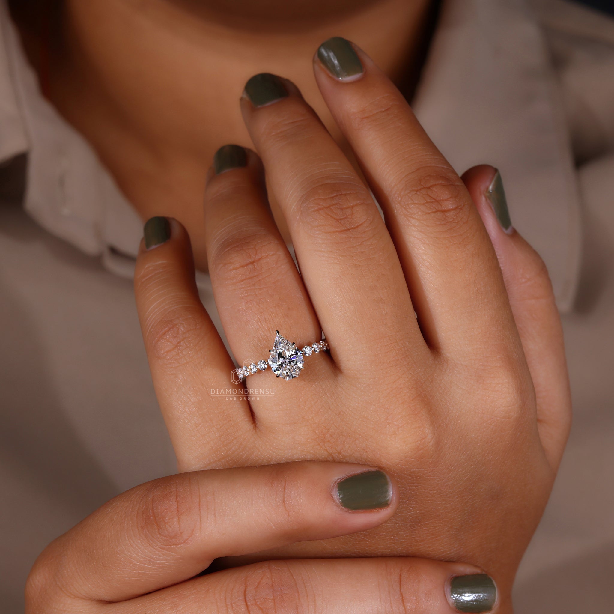 Model showcasing a modern engagement ring with a spear cut diamond and claw prongs.