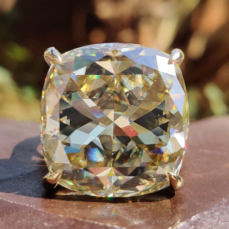 Cushion moissanite ring with light yellow center stone.
