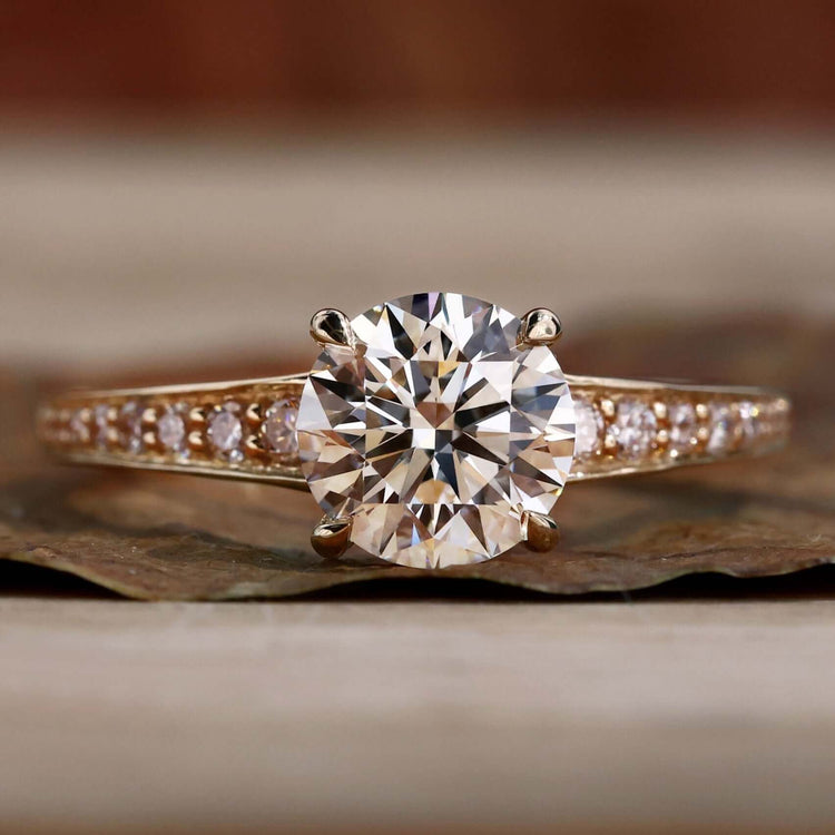 Gold engagement ring with a round brilliant engagement ring design and a 4 prong claw setting for timeless elegance.
