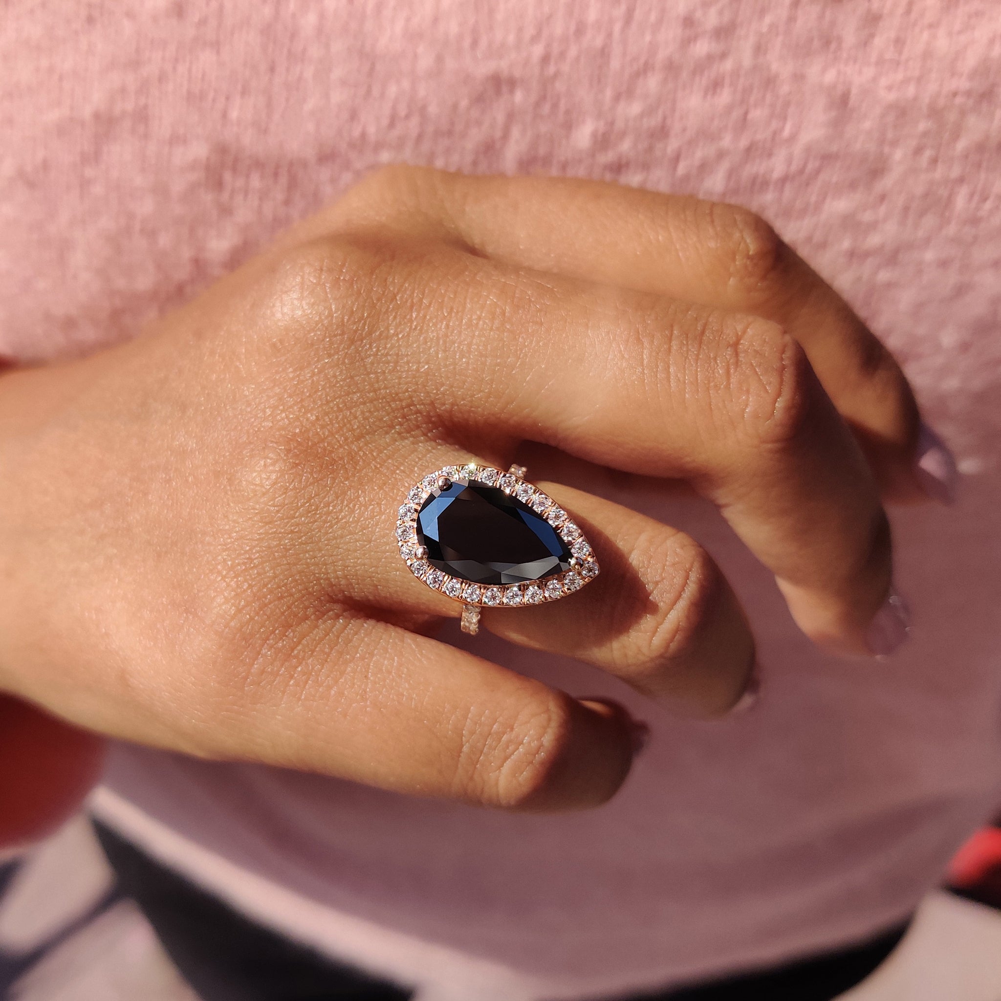 Black moissanite ring with round cut halo and rose gold engagement setting.
