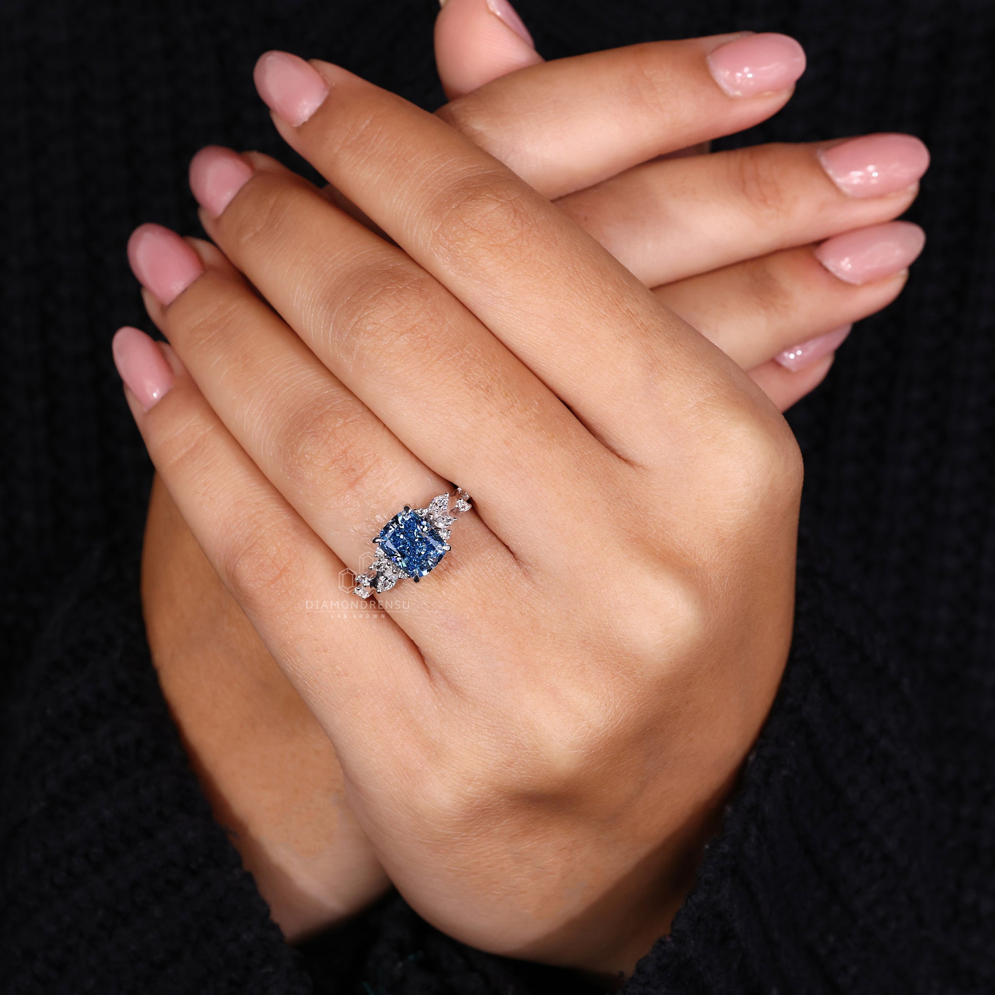 White gold engagement ring with 4 prong claw setting and blue diamond.
