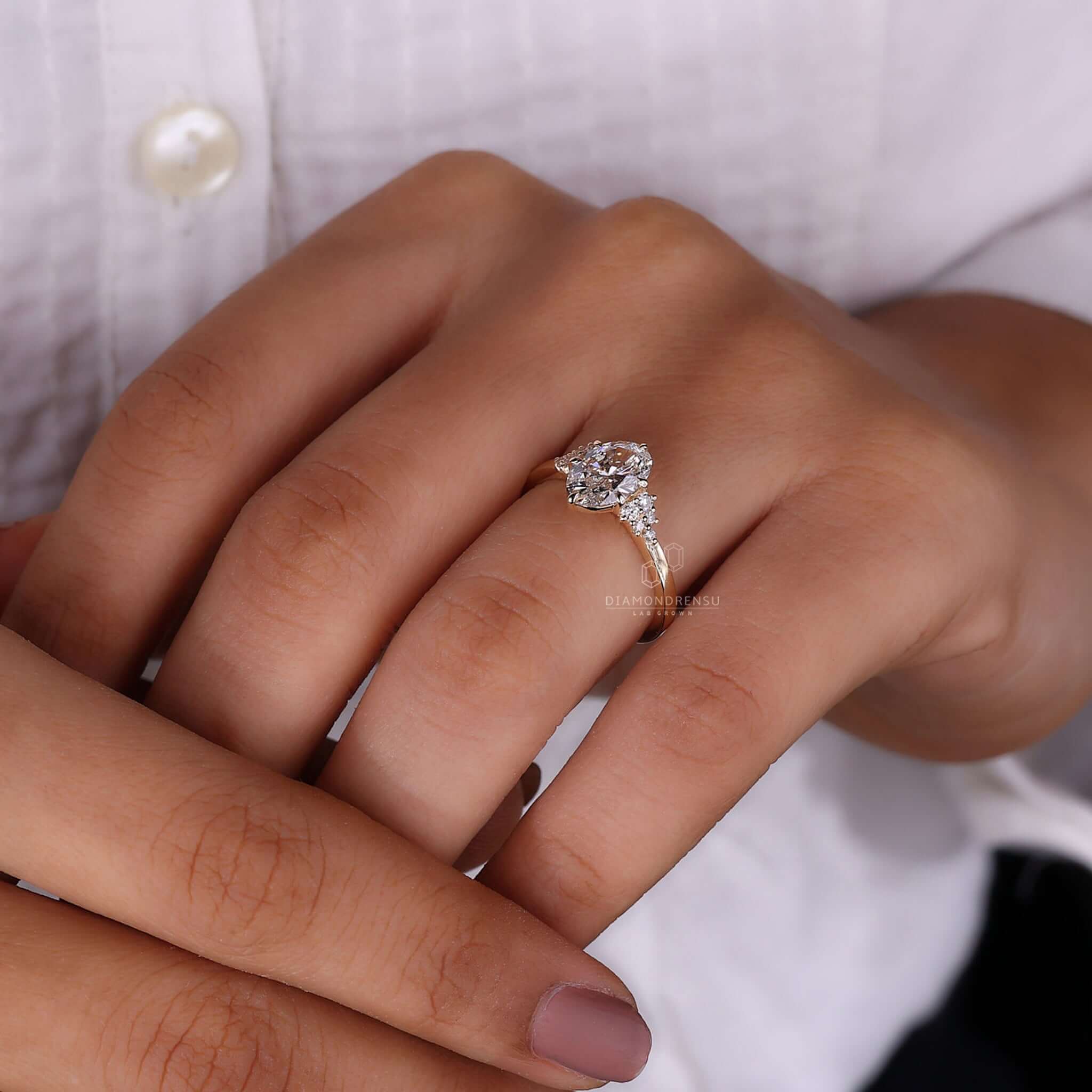 Gold proposal ring with an oval diamond on a model's finger