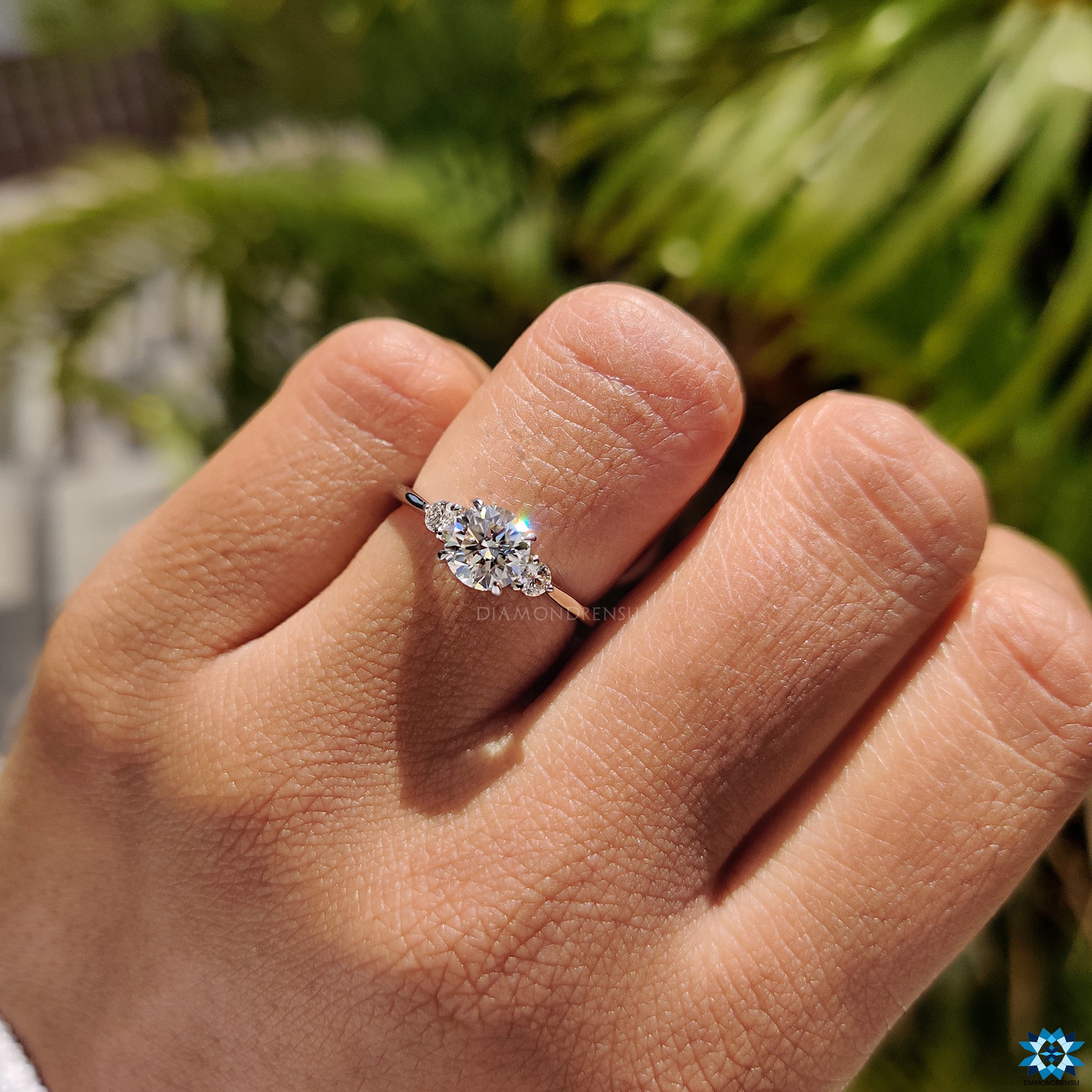 Two round side stone moissanites set beside main engagement gem.
